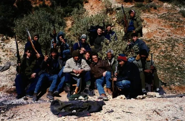 Ομαδικό πορτρέτο περίπου δεκαπέντε ένοπλων ανδρών σε πλαγιά με ελιές, Αλβανία, 1997.