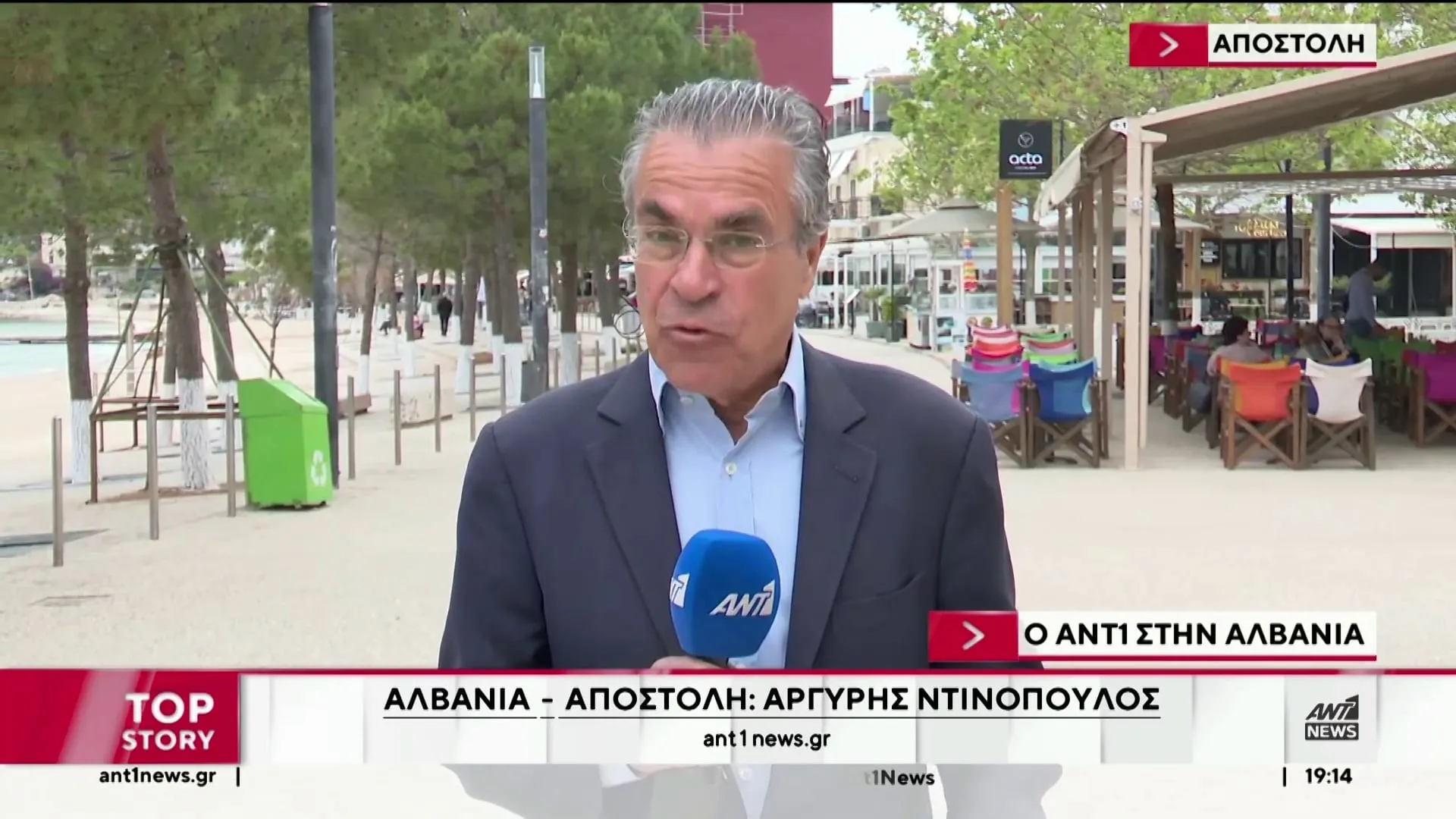 Ο Αργύρης Ντινόπουλος σε ζωντανή σύνδεση με μικρόφωνο του ΑΝΤ1, με τον παραλιακό πεζόδρομο της Χειμάρρας πίσω του.
