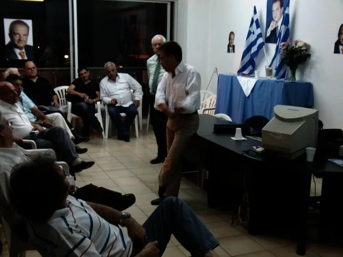 Ο Αργύρης Ντινόπουλος μιλά σε προεκλογική εκδήλωση κάτω από πανό.