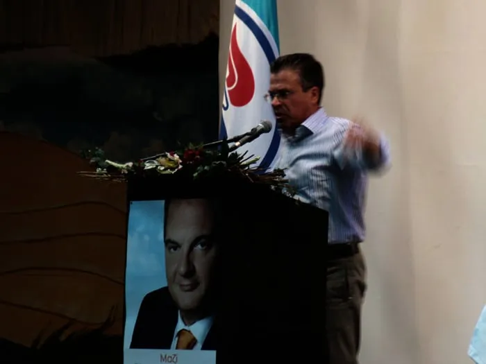 Ο Αργύρης Ντινόπουλος μιλά από βήμα σε προεκλογική εκδήλωση.