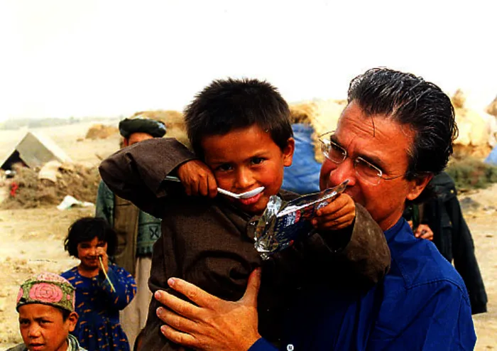 Argyris Dinopoulos helping a child at a refugee camp in Afghanistan
