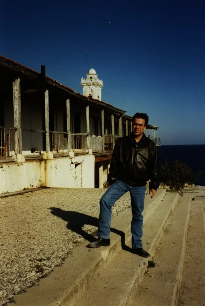 Ο ανταποκριτής Αργύρης Ντινόπουλος στην ταράτσα ερειπωμένου κτιρίου με θέα στη θάλασσα και φάρο πίσω του, κατεχόμενη Κύπρος, 2002.