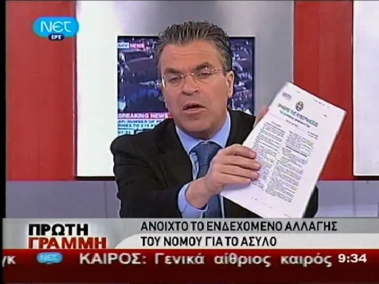Στιγμιότυπο τηλεοπτικής εκπομπής της ΝΕΤ, «ΠΡΩΤΗ ΓΡΑΜΜΗ»: ο Αργύρης Ντινόπουλος, με σκούρο σακάκι και γαλάζια γραβάτα, υψώνει ένα τυπωμένο έγγραφο προς τον φακό, ενώ στο κάτω πλαίσιο της οθόνης εμφανίζεται ο τίτλος «Ανοιχτό το ενδεχόμενο αλλαγής του νόμου για το άσυλο».