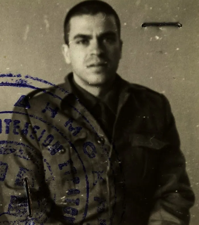 Ασπρόμαυρη φωτογραφία τύπου ταυτότητας ενός νεαρού άνδρα με στρατιωτική στολή, με επίσημη σφραγίδα.