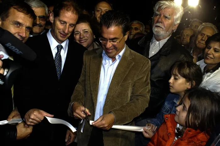 Βραδινή κοπή κορδέλας με ένα μικρόφωνο τύπου μπροστά, πλήθος και φώτα στο βάθος.