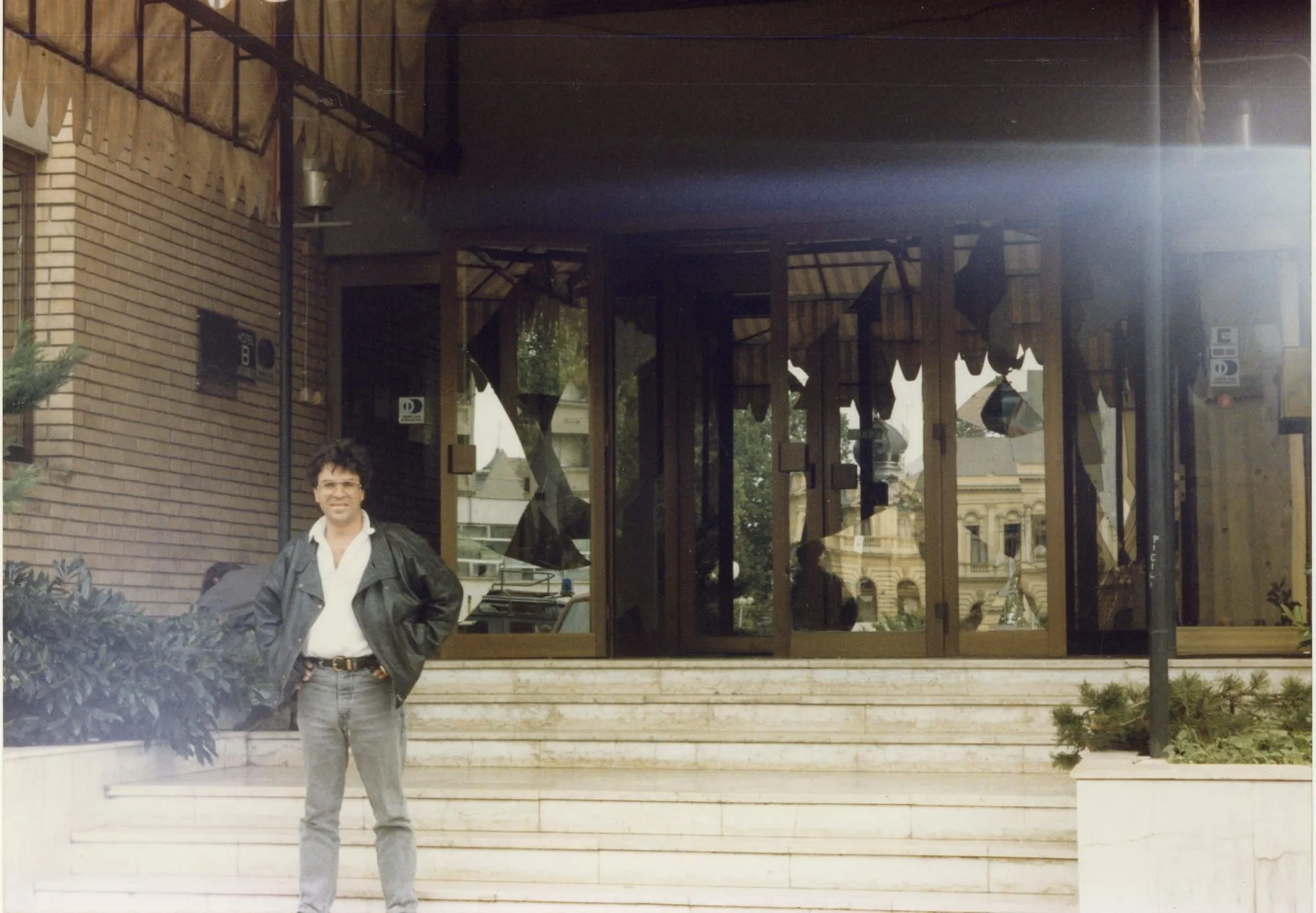 Ο Αργύρης Ντινόπουλος μπροστά σε είσοδο ξενοδοχείου με θρυμματισμένη τζαμαρία, Βούκοβαρ, 1991.